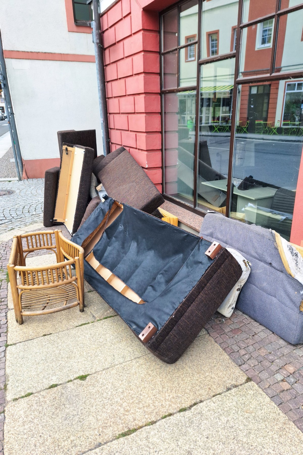 A pile of discarded furniture including a sofa, chair, and various cushions