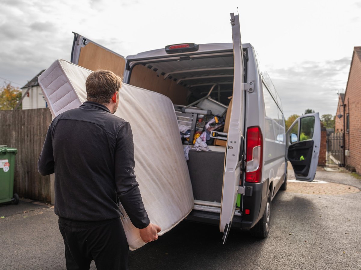 Man carrying and loading a mattress into a removal van